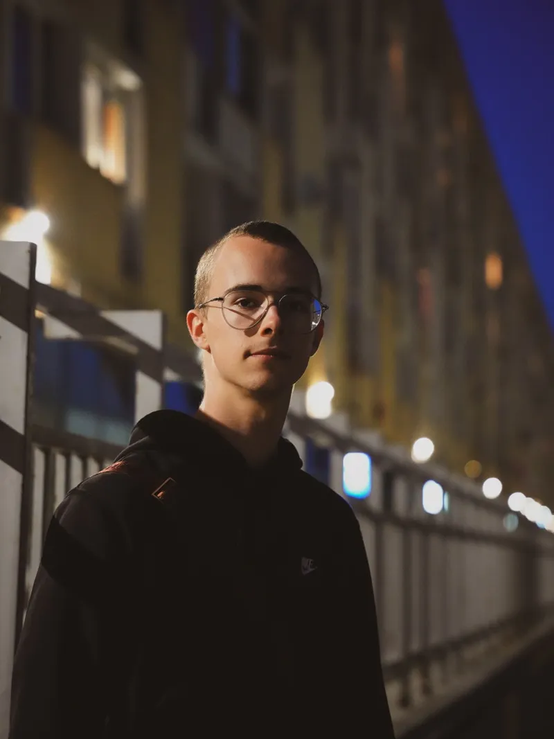 Nocny portret chłopaka w okularach na moście