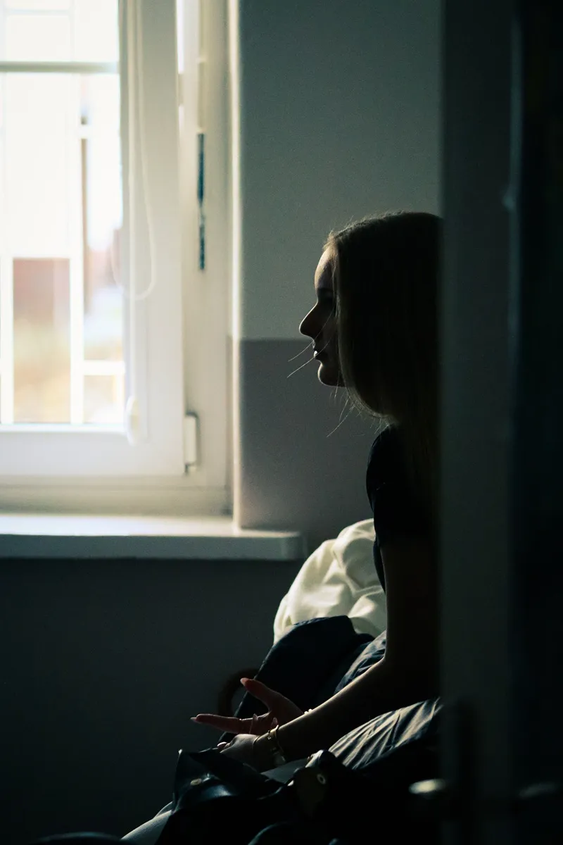 Sylwetka kobiety przy oknie w półmroku