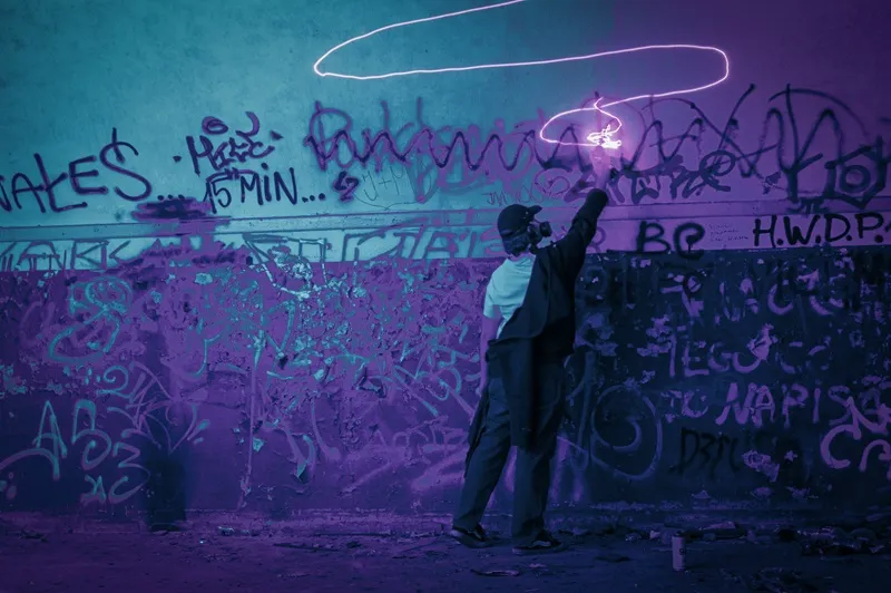 Mężczyzna przy ścianie z graffiti w fioletowym świetle